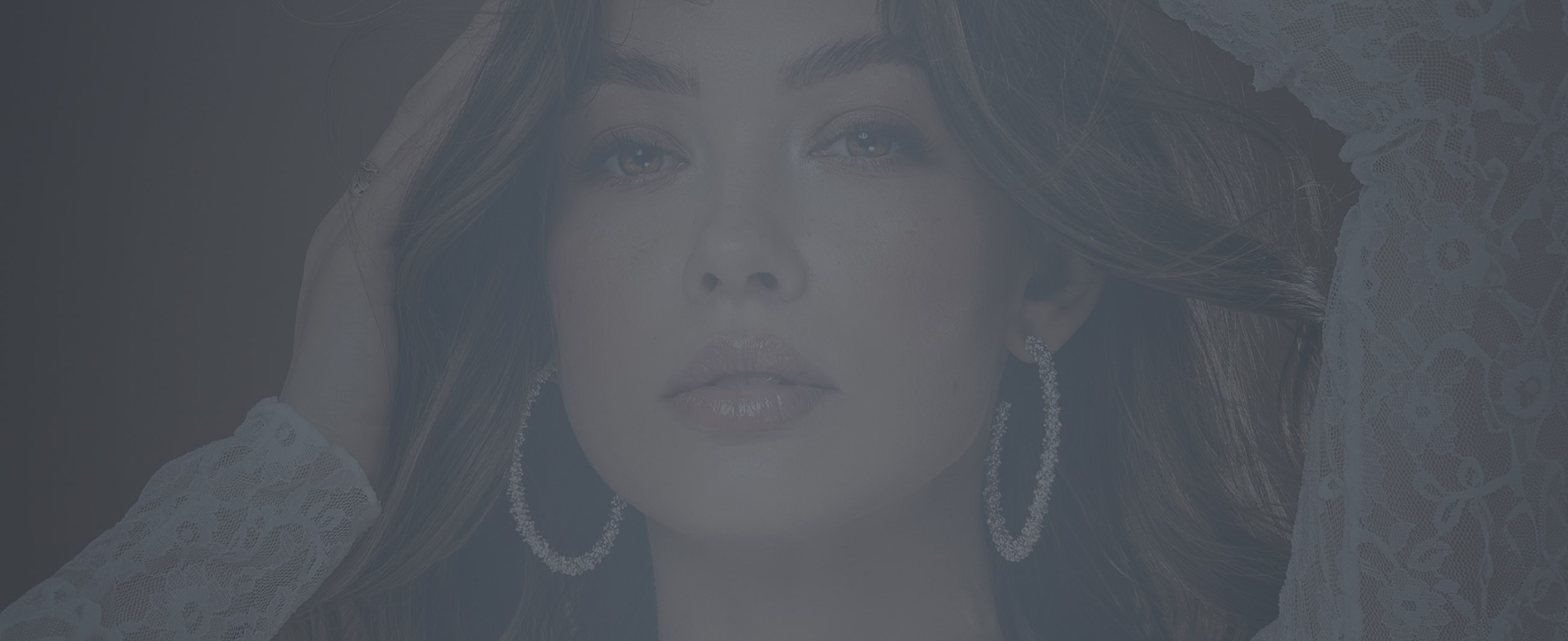 Close-up of a woman with earrings and natural makeup.