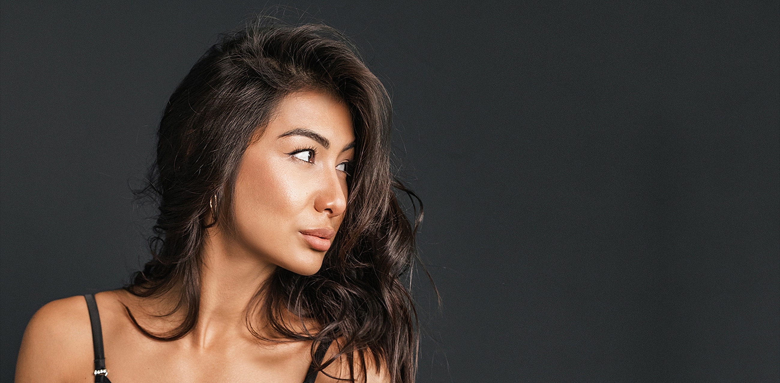 Profile of a woman with dark, wavy hair.