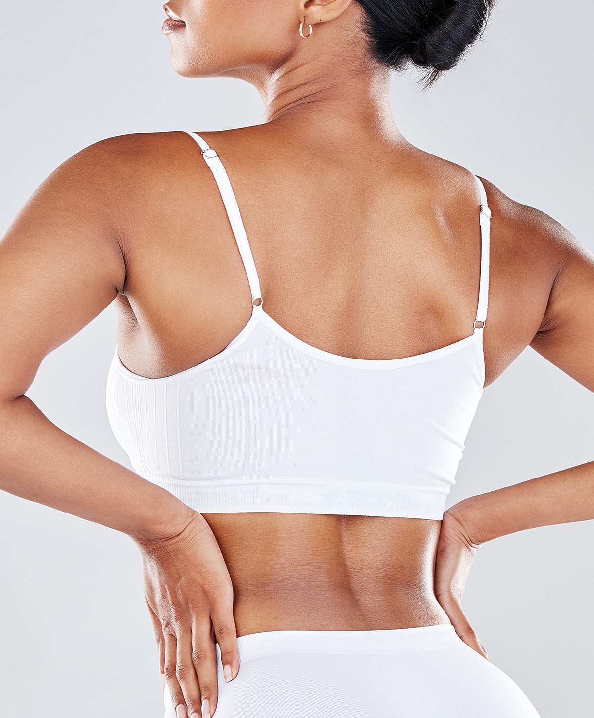 Woman wearing white athletic bra from behind.