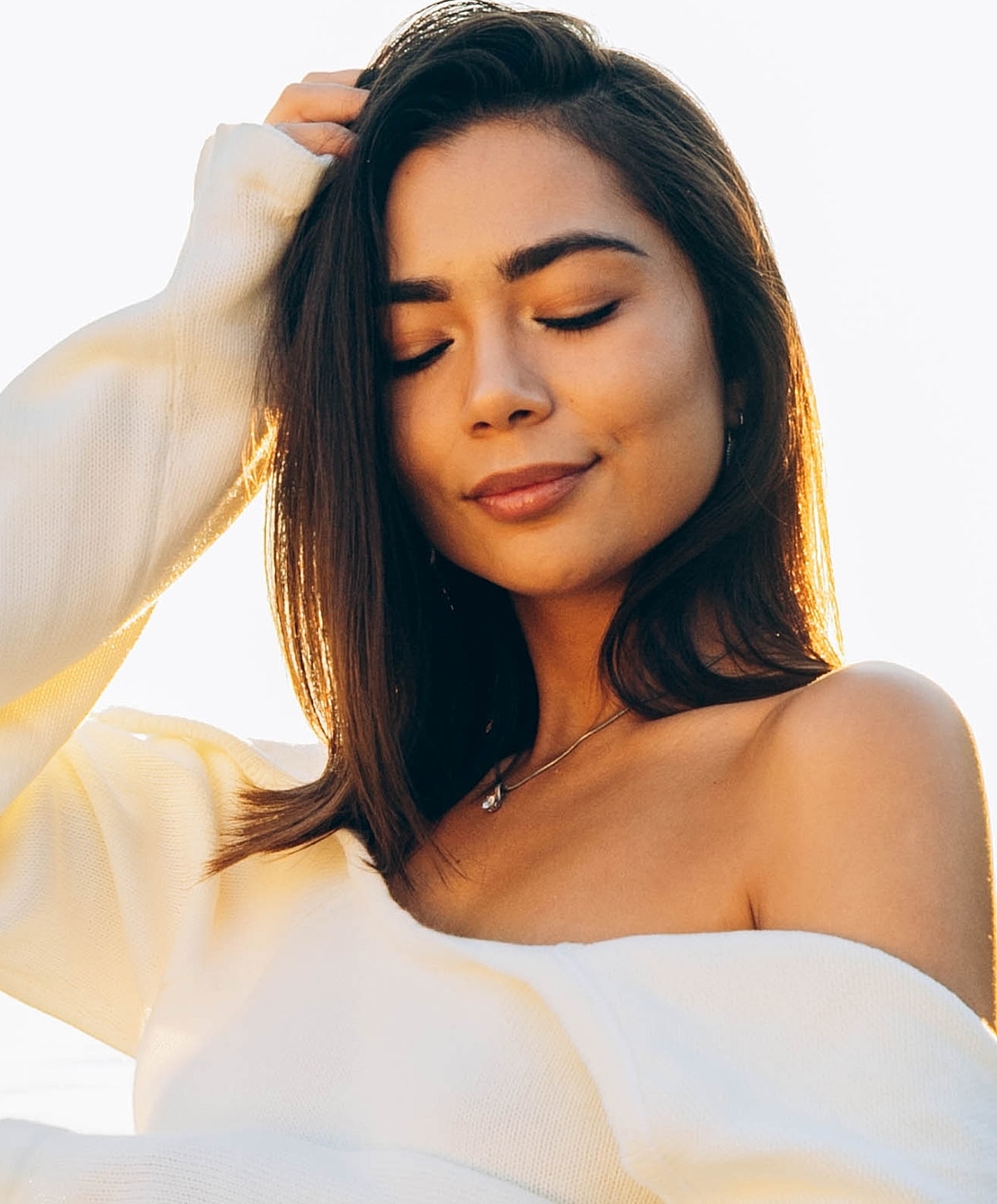 Woman with closed eyes, soft sunlight glow.
