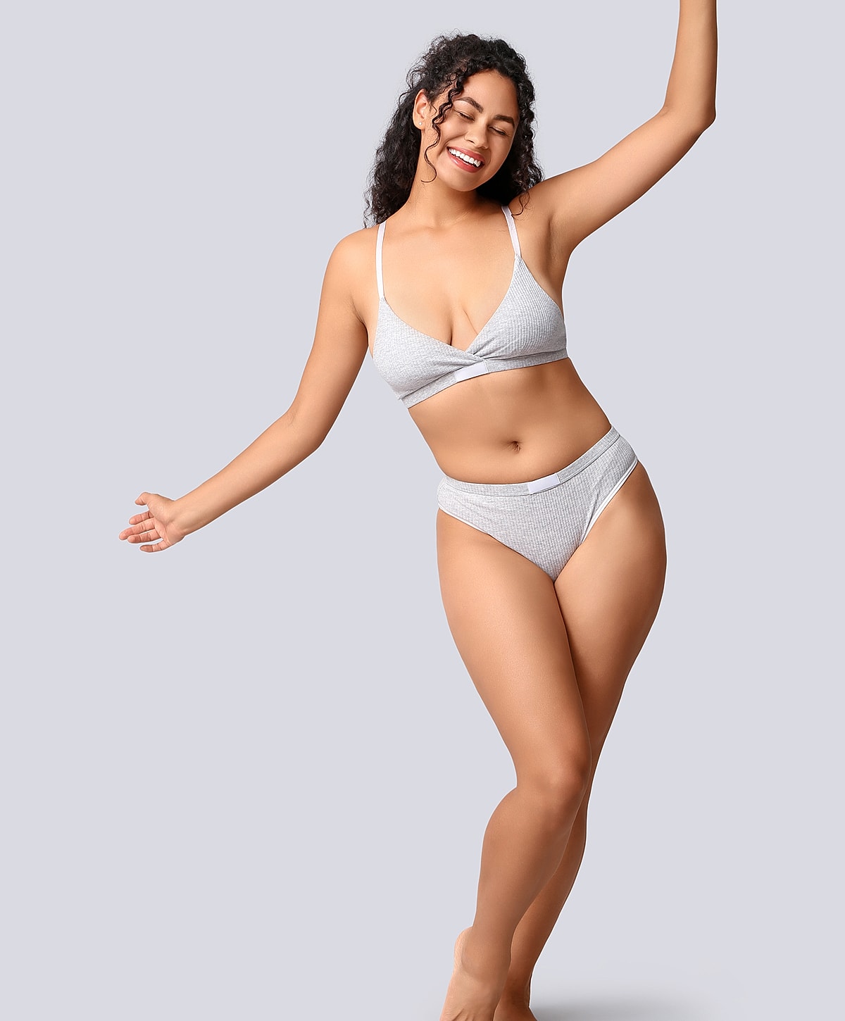 Woman in gray bikini smiling and dancing.