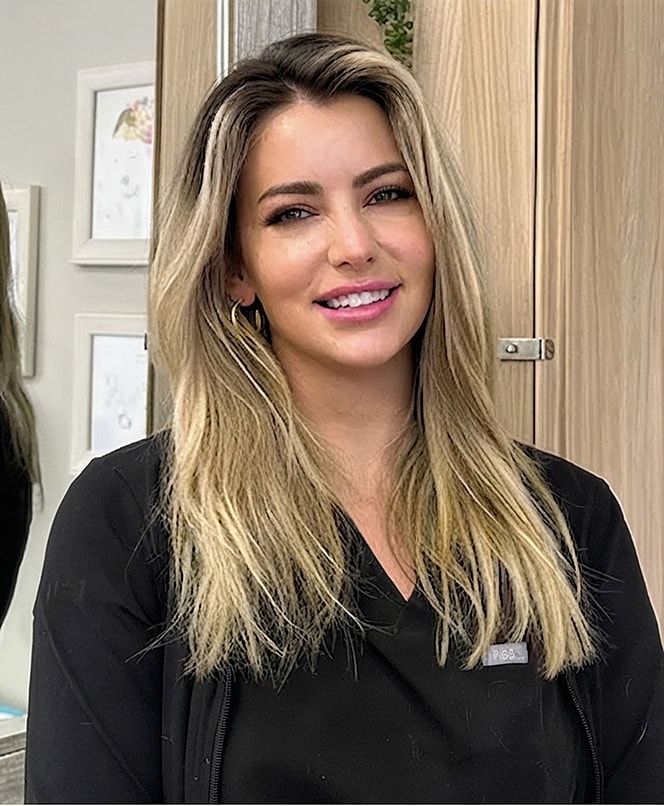Smiling woman wearing a black uniform in salon.
