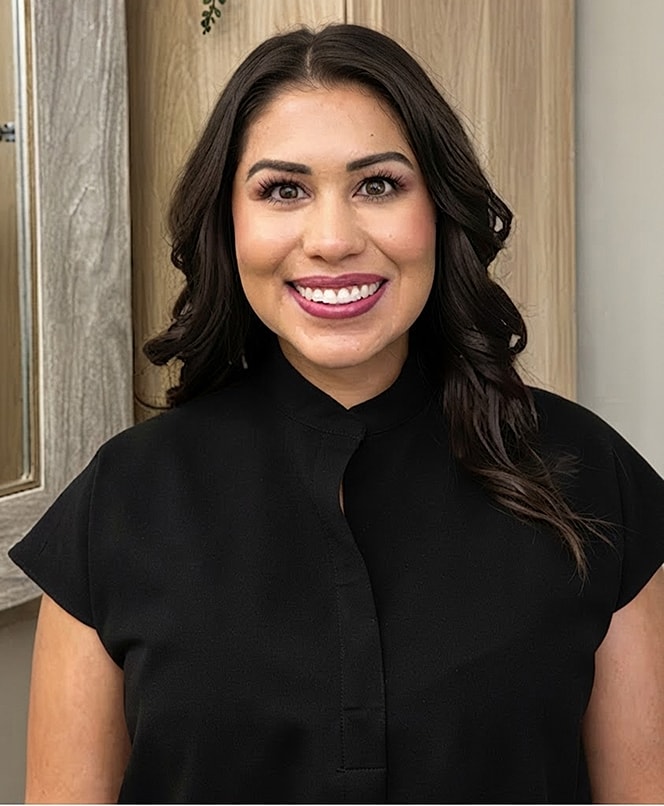 Smiling woman in black attire, neutral background.