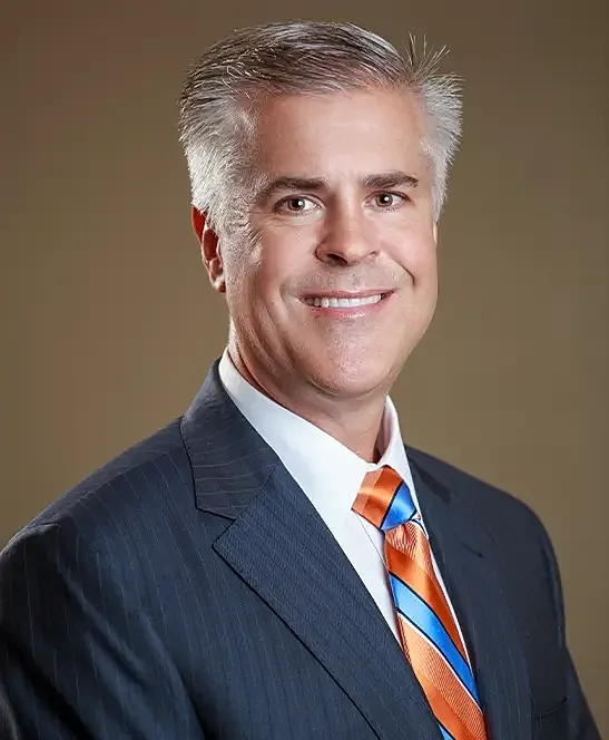 Smiling man in a suit with colorful tie.