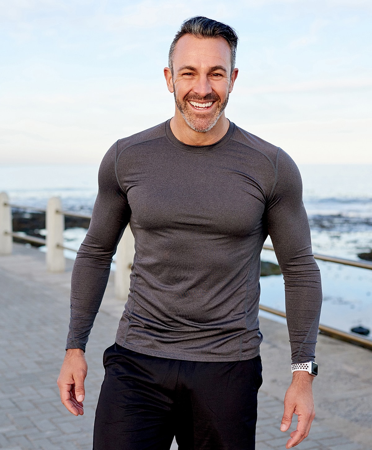 Smiling man in activewear by the ocean.