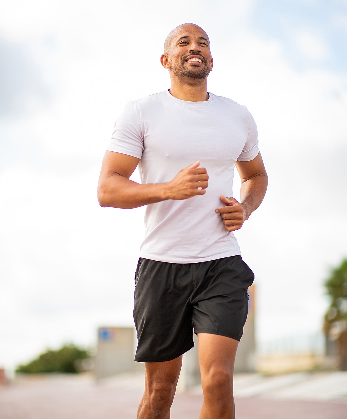Smiling man running outdoors in athletic clothing.