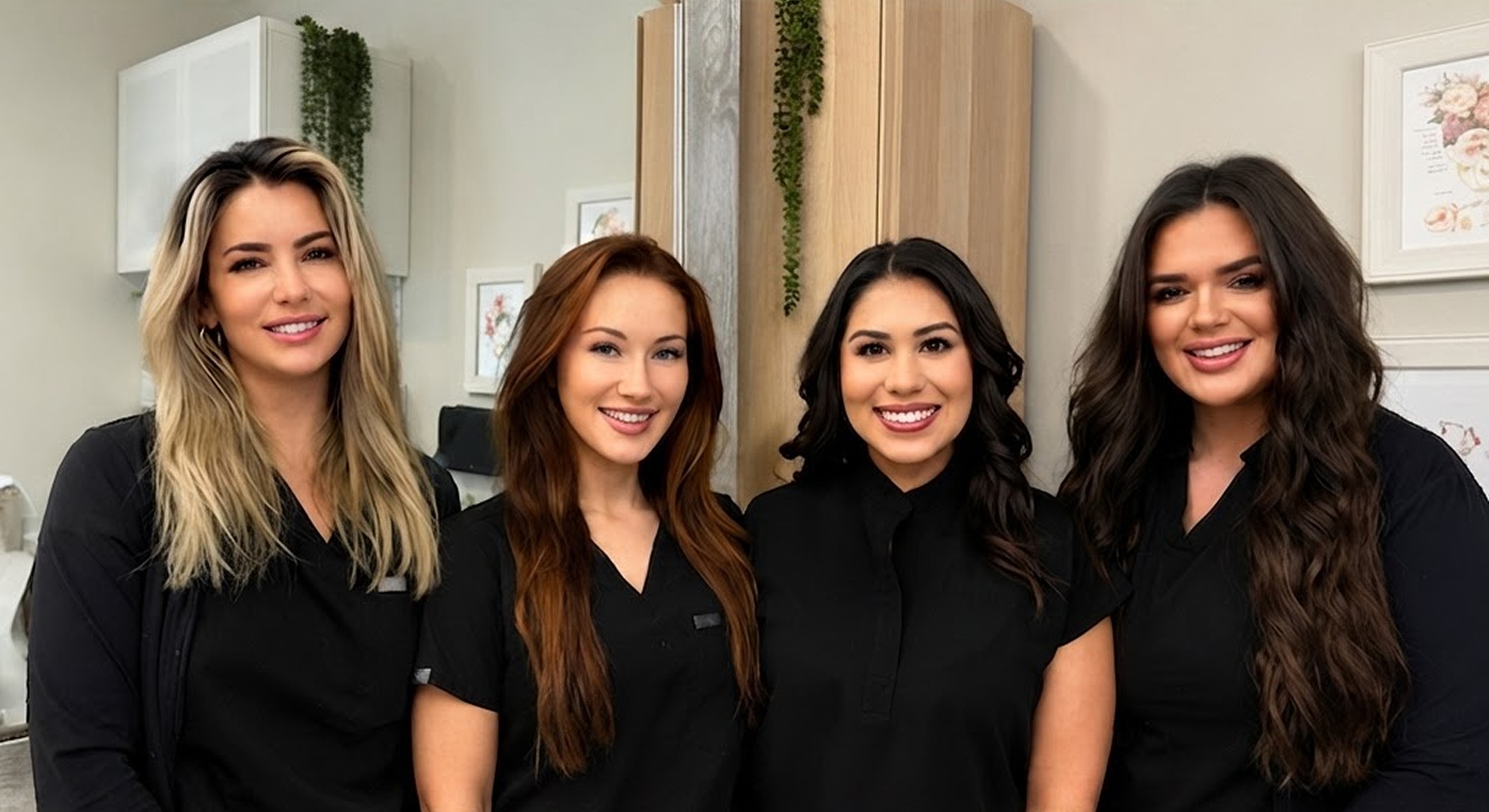 Four women in black uniforms smiling together.