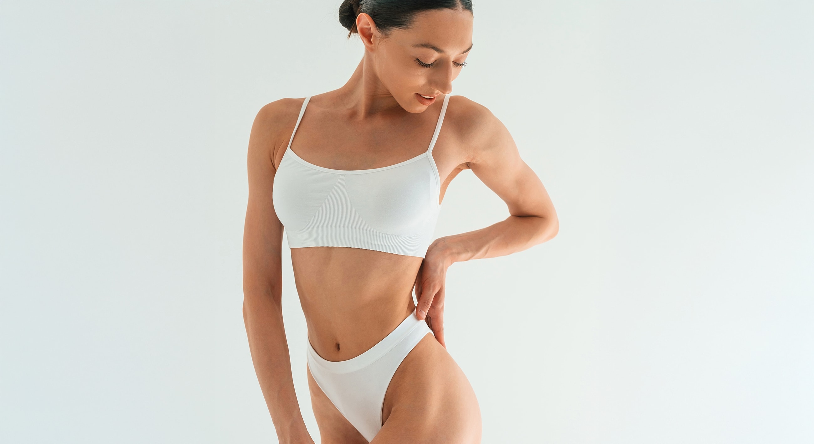 Model posing in white activewear against white background.