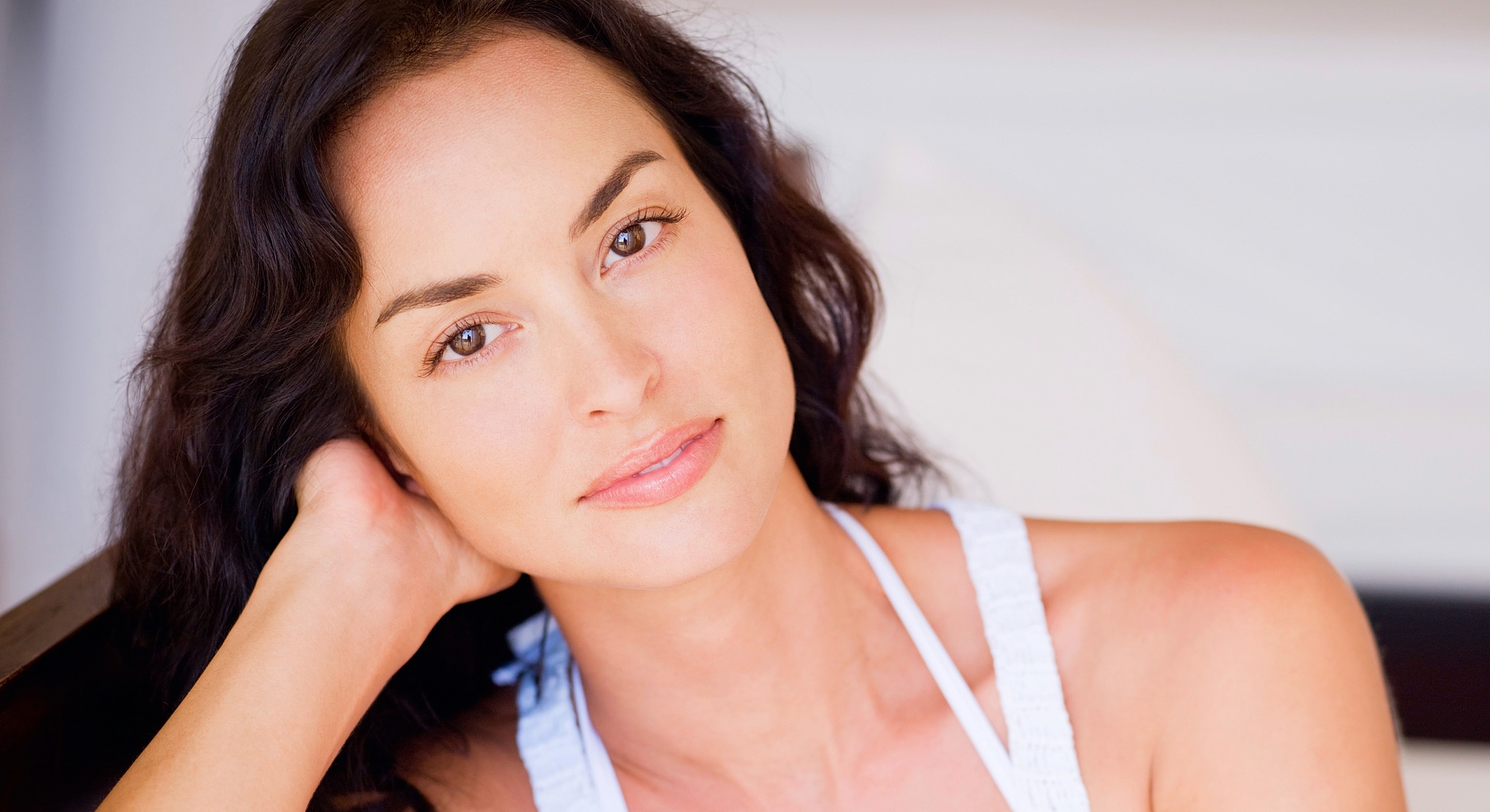 Smiling woman resting her chin on hand.