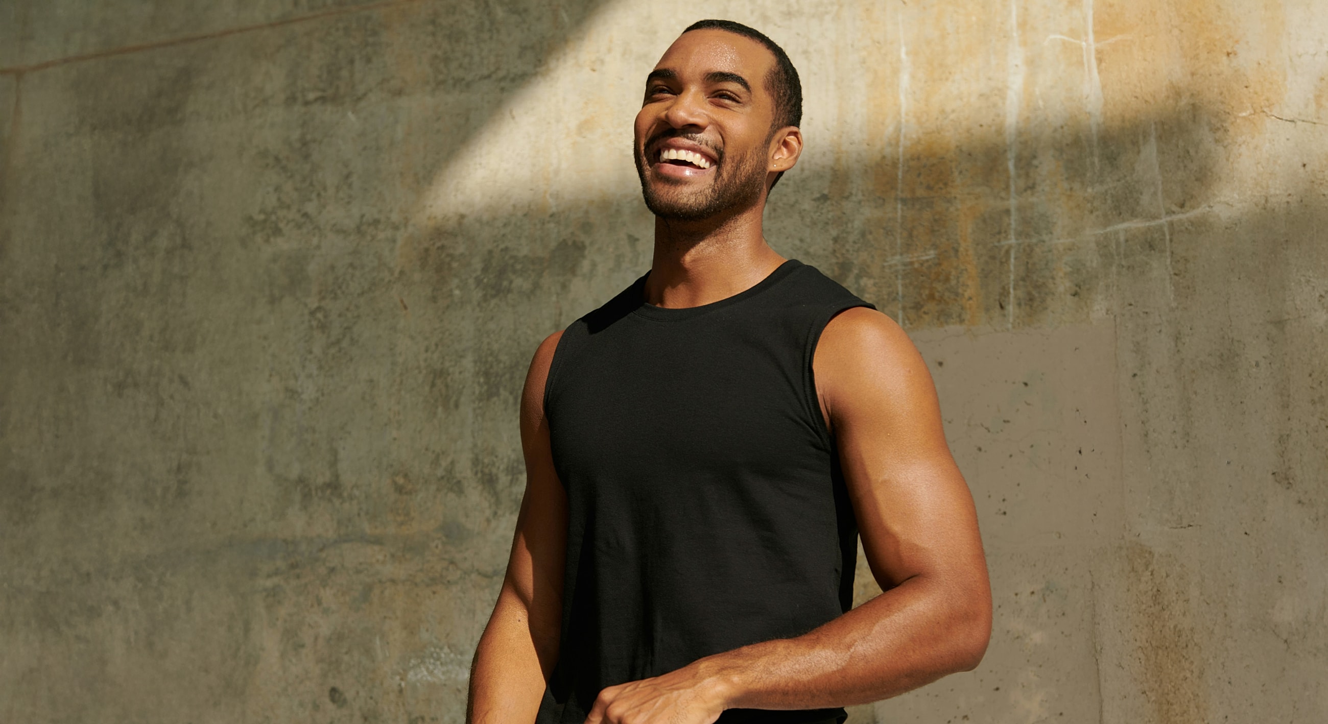 Smiling man in a sleeveless black shirt.