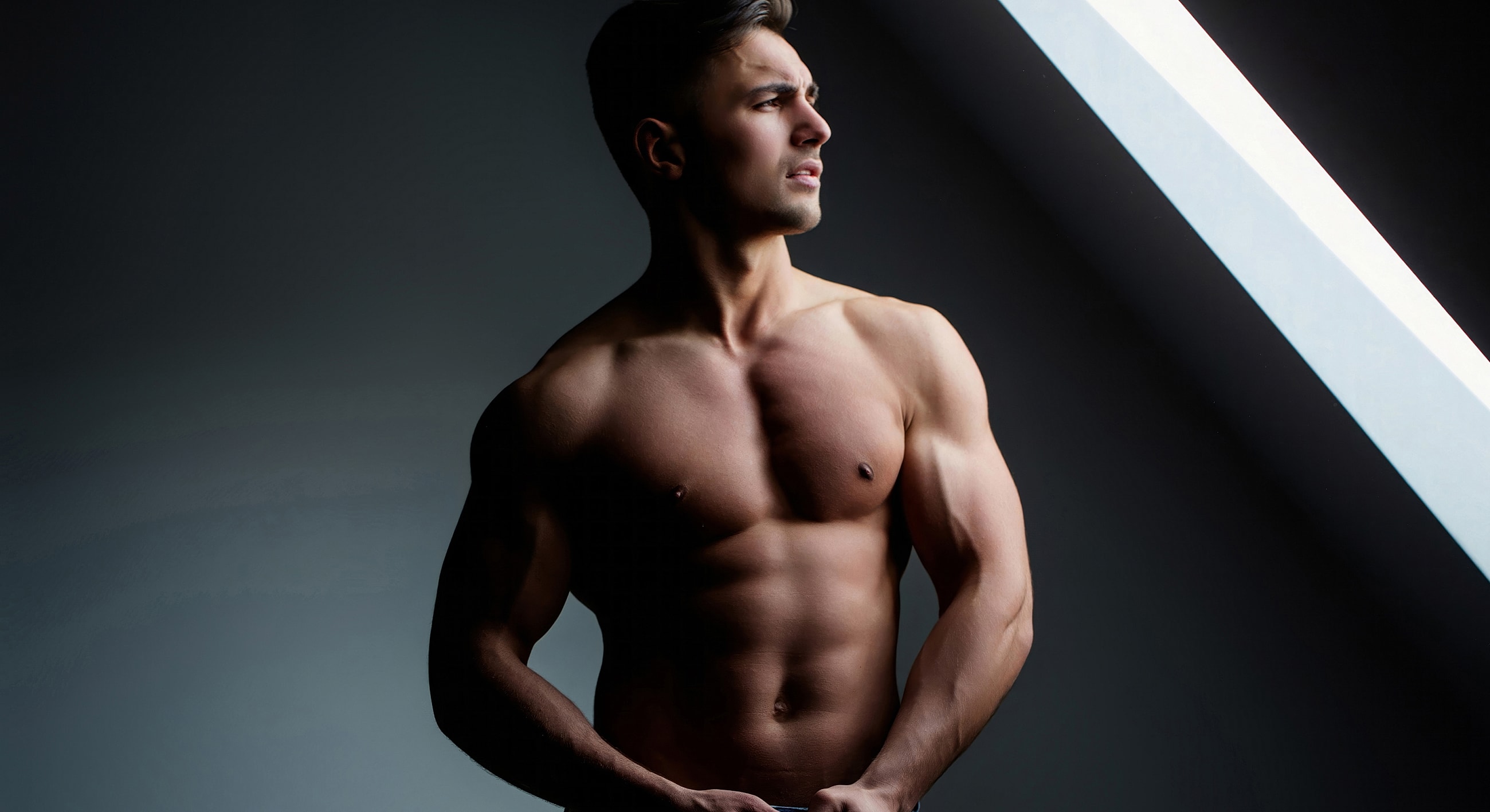 Muscular man posing in dramatic lighting.