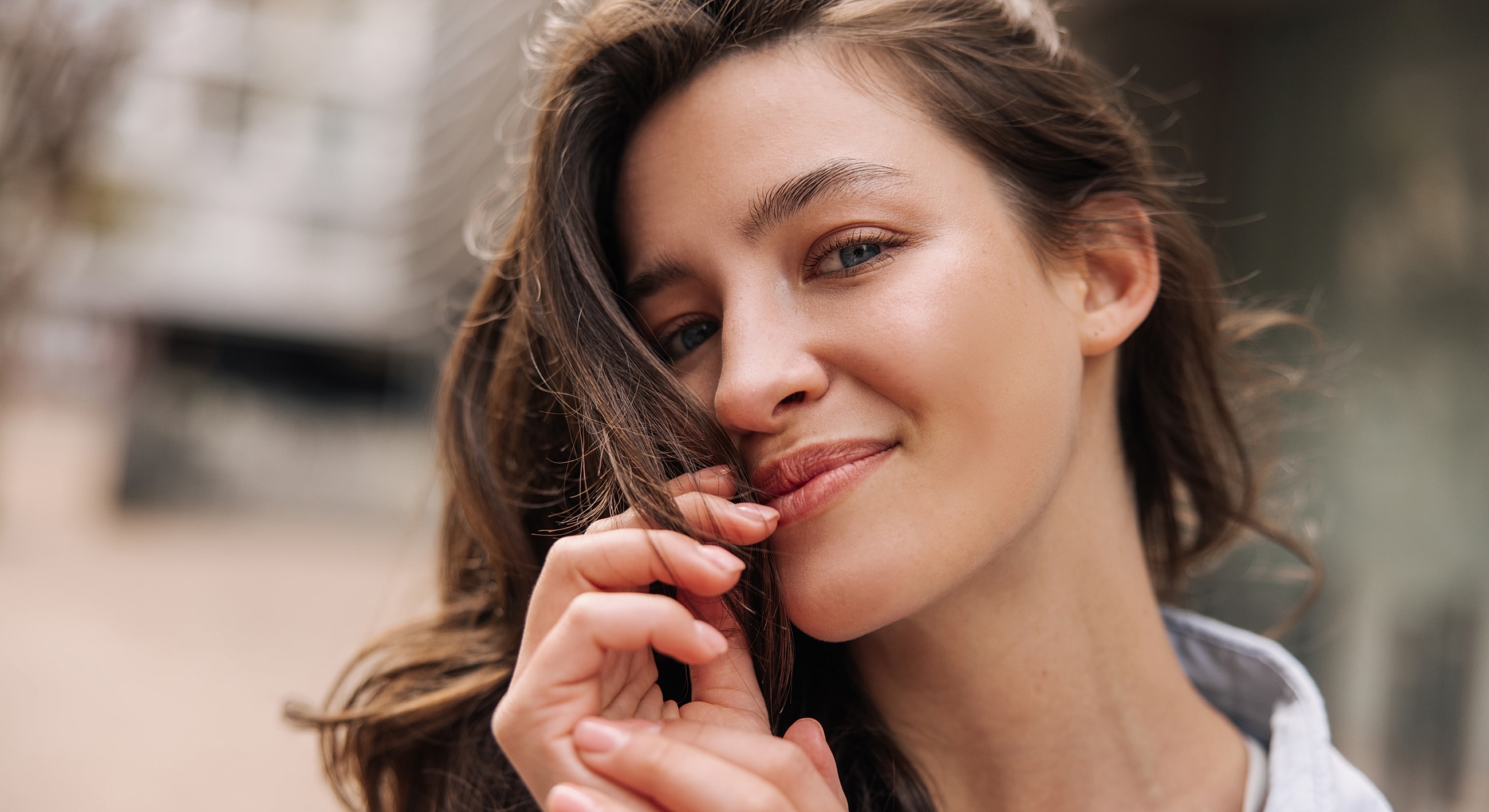 Smiling woman touching her hair outdoors.