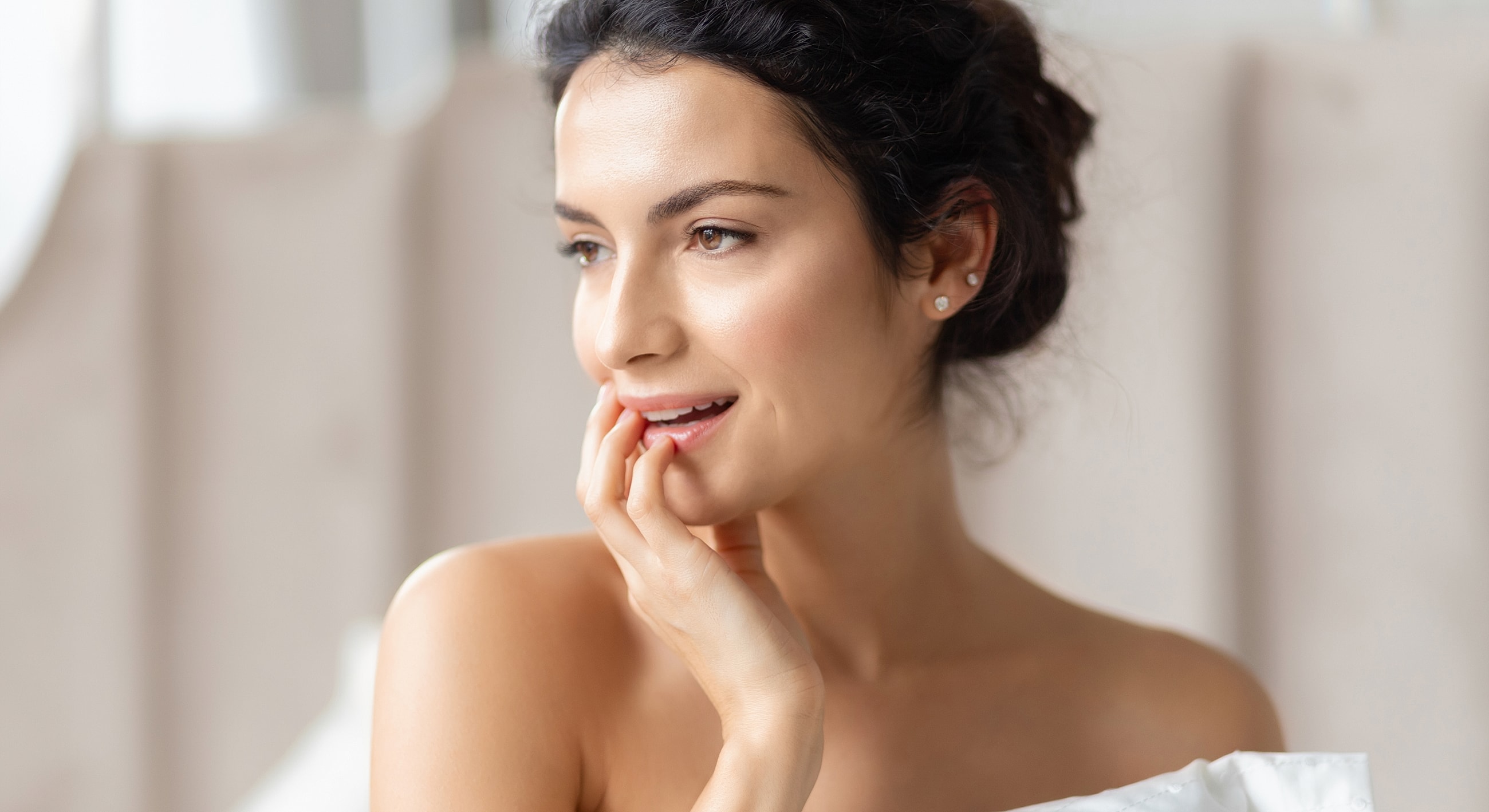Smiling woman touching her face thoughtfully.