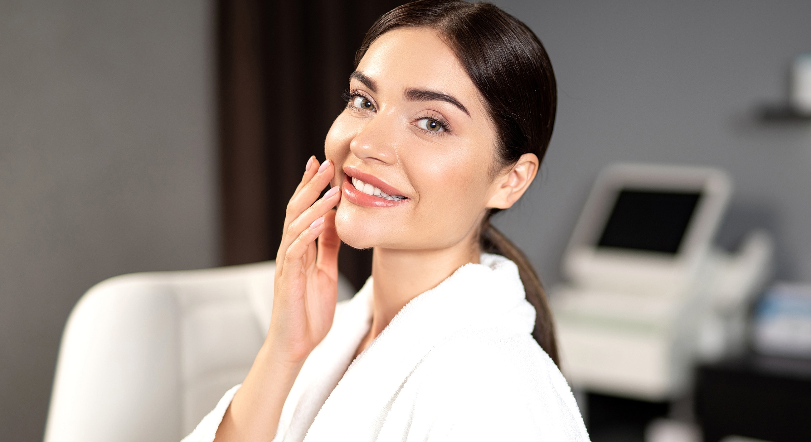 Smiling woman in a spa setting wearing robe.