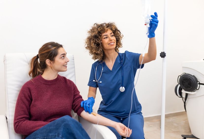 nurse administering IV therapy to a young woman
